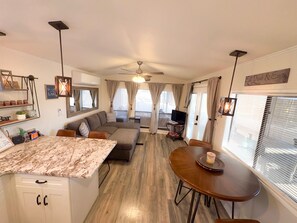 A compact living space with a kitchenette, a dining area, a sofa, and a ceiling fan. - Boat Days and Beachcomber Nights (Lake Havasu City)