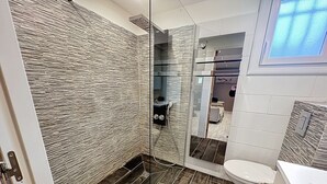 A modern bathroom with a glass shower enclosure, a toilet, and a sink.