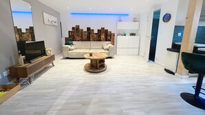 A modern living room with a sofa, coffee table, TV, and wooden flooring.