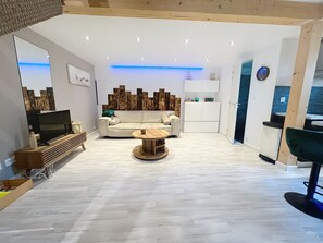A modern living room with a sofa, coffee table, TV, and wooden flooring.