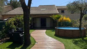 A house with a tiled roof, a wooden deck, a swimming pool, and a lawn.