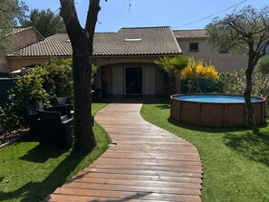 A house with a tiled roof, a wooden deck, a swimming pool, and a lawn.