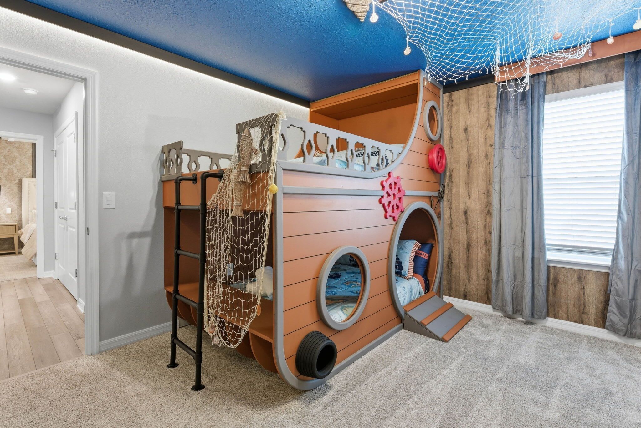 A children's play area with a bunk bed, netted play space, and a window with curtains.