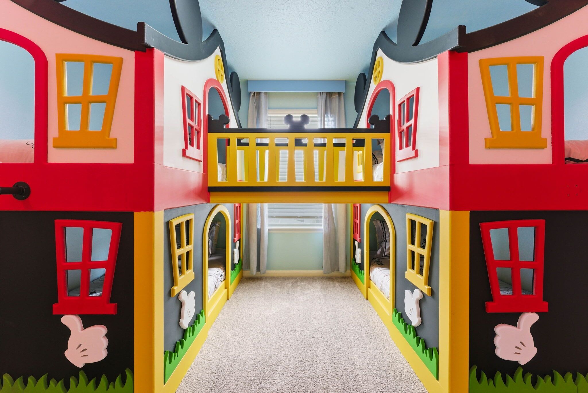 A children's playroom with a central walkway, two-story playhouse with windows, and a balcony.