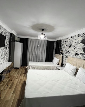 A hotel room with two beds, a dining area, and a modern chandelier.. Istanbul Palas Otel