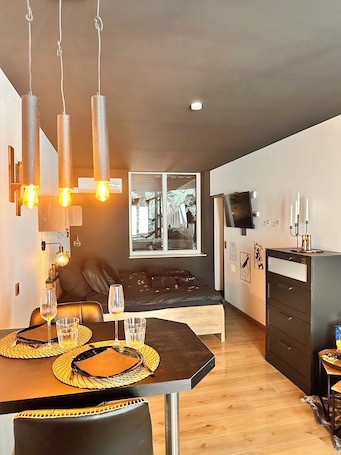 A modern room with a dining table, chairs, a sofa, and a TV on the wall.. The Secret Rock
