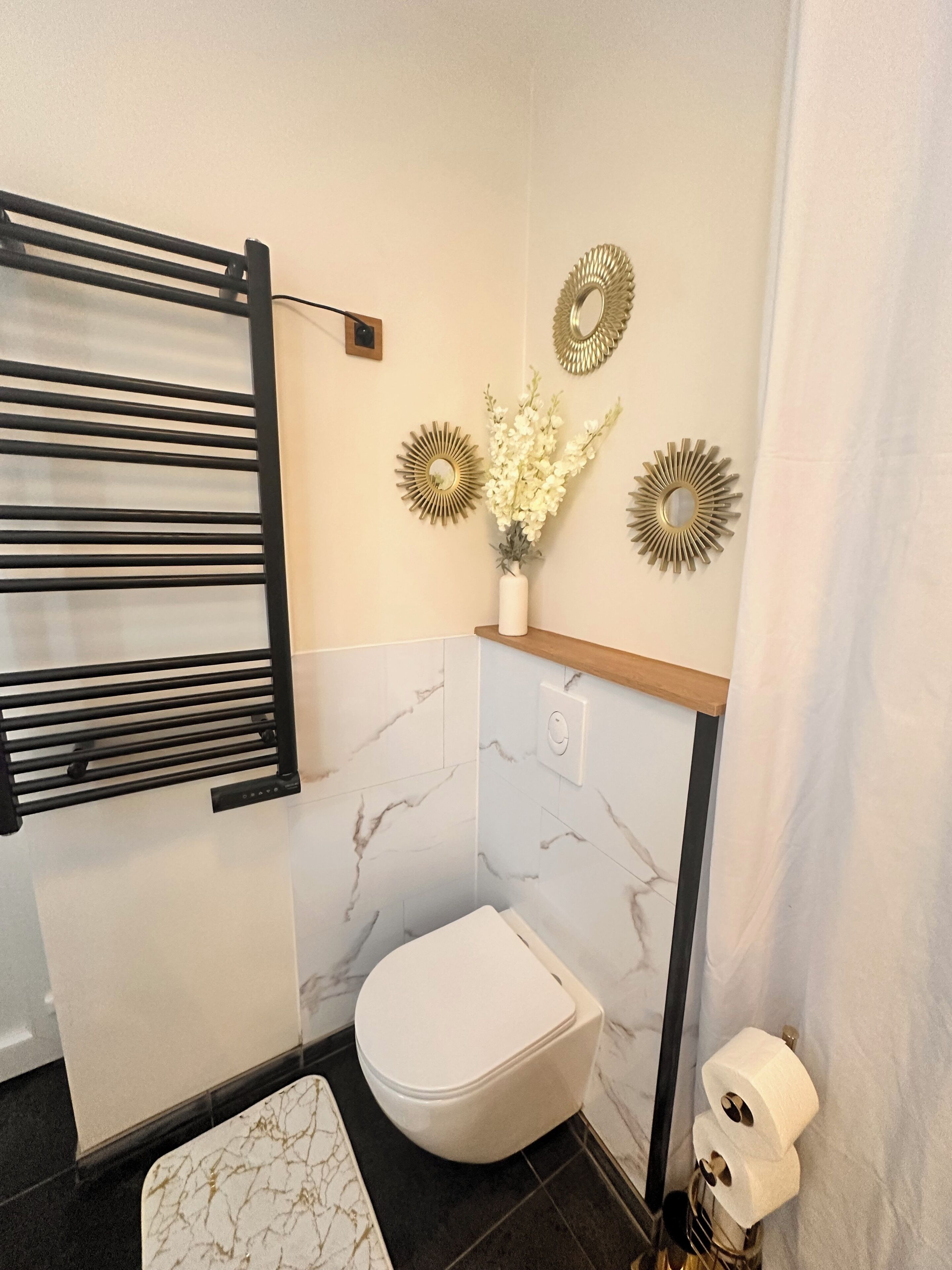 Une salle de bain équipée de toilettes, d’un porte-serviettes et de miroirs décoratifs fixés au mur.