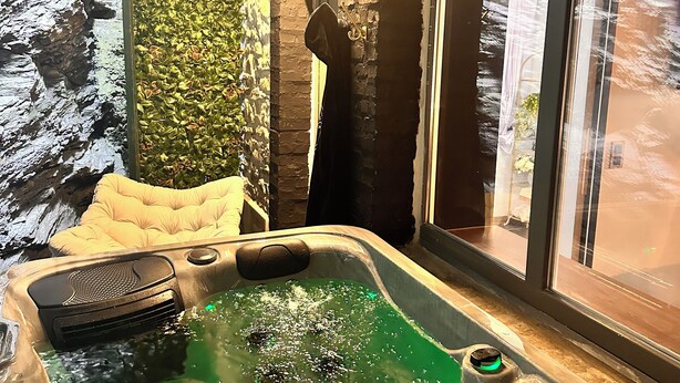 A hot tub with a wooden ceiling and a stone wall. - The Secret Rock (La Roche-en-Ardenne)