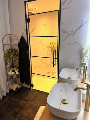 Ein Badezimmer mit Marmorwaschtisch, Waschbecken, Spiegel und einer Tür zu einem anderen Raum.
