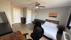 A bedroom with a bed, a desk, a chair, a dresser, a ceiling fan, and a painting on the wall. - Luxury Condo Stay in the Heart of Atlanta (Atlanta)