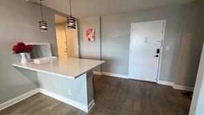 A room with a white countertop, a mirror, a vase with red flowers, and a door. - Luxury Condo Stay in the Heart of Atlanta (Atlanta)