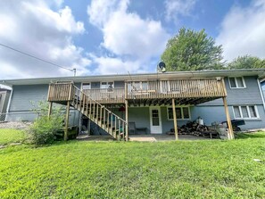 A two-story house with a wooden deck, a staircase, and a garage.