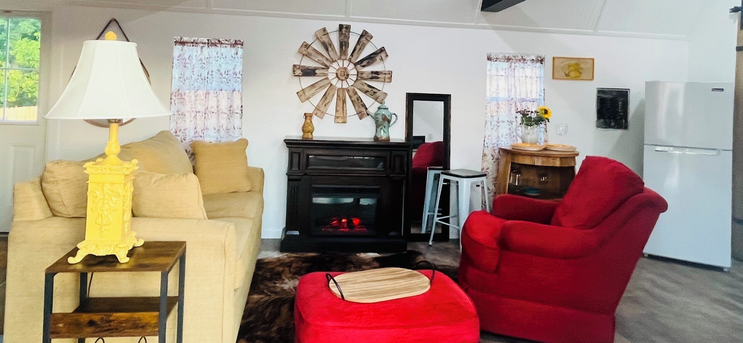 Un salon comprenant un canapé, un fauteuil rouge, une lampe, une cheminée et un élément décoratif mural.