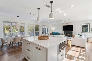 Une cuisine moderne dotée d’un îlot central, d’un coin repas avec des chaises, d’une cheminée et d’un espace salon avec un canapé.