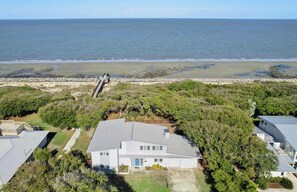 Une propriété située sur la côte, comprenant une grande maison, un mur en pierre et une vue sur la plage.