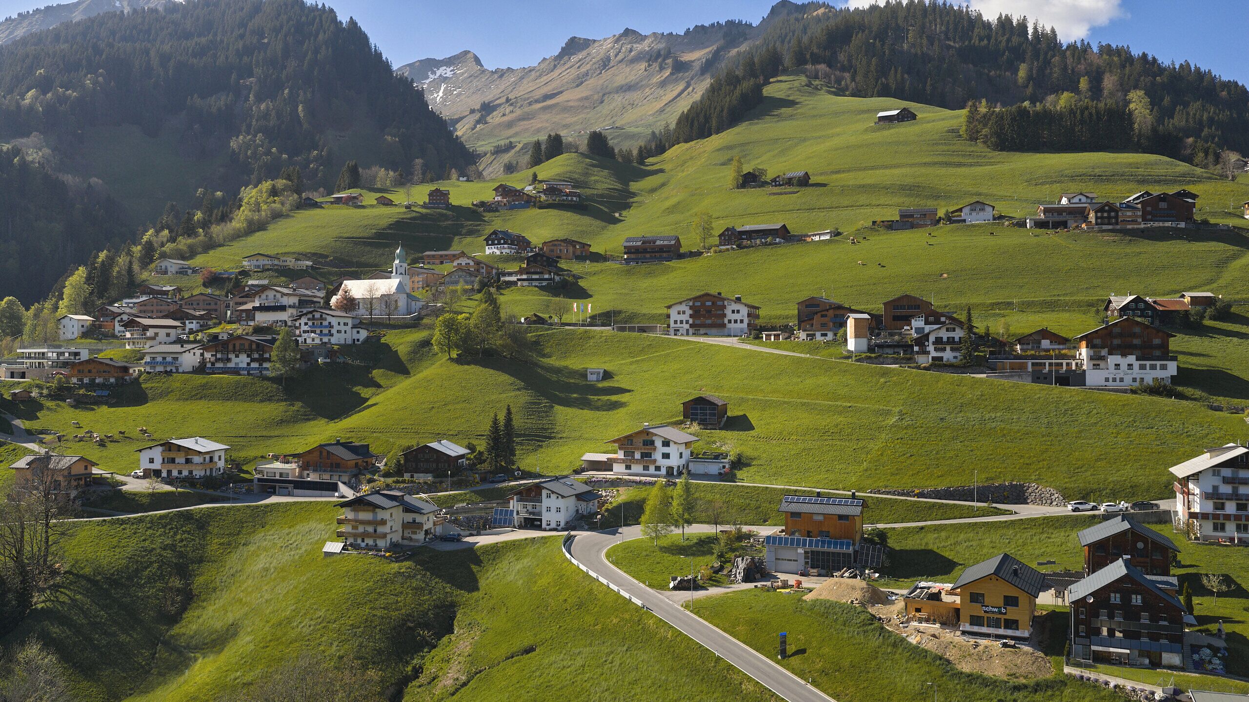 A hillside village with houses, a church, and a winding road.