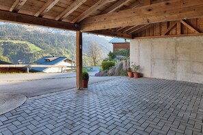 Ein überdachter Außenbereich mit Backsteinboden, Holzbalken und Blumentöpfen.