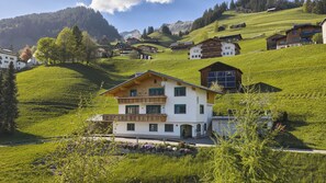 Ein mehrgeschossiges Gebäude mit Balkonen, gelegen an einem Hügel mit Blick auf umliegende Häuser und Berge.