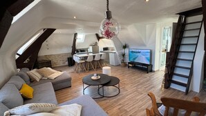 A loft-style living space with a dining area, kitchen, and a TV.