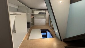 A modern interior with a wooden floor, white built-in storage units, and a staircase.