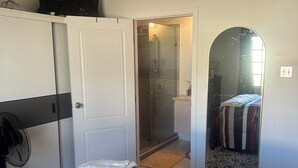 Una camera da letto con un letto, un armadio, uno specchio e un angolo doccia.