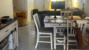 Zona pranzo con tavolo, sedie, divano e televisione.