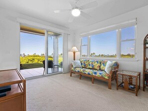 Una habitación con sofá, mesa, lámpara y vistas al exterior.