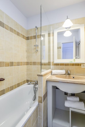 A bathroom with a bathtub, a sink, a mirror, and a towel rack. - Family Apartment for 4 in Ardeche (Grospierres)
