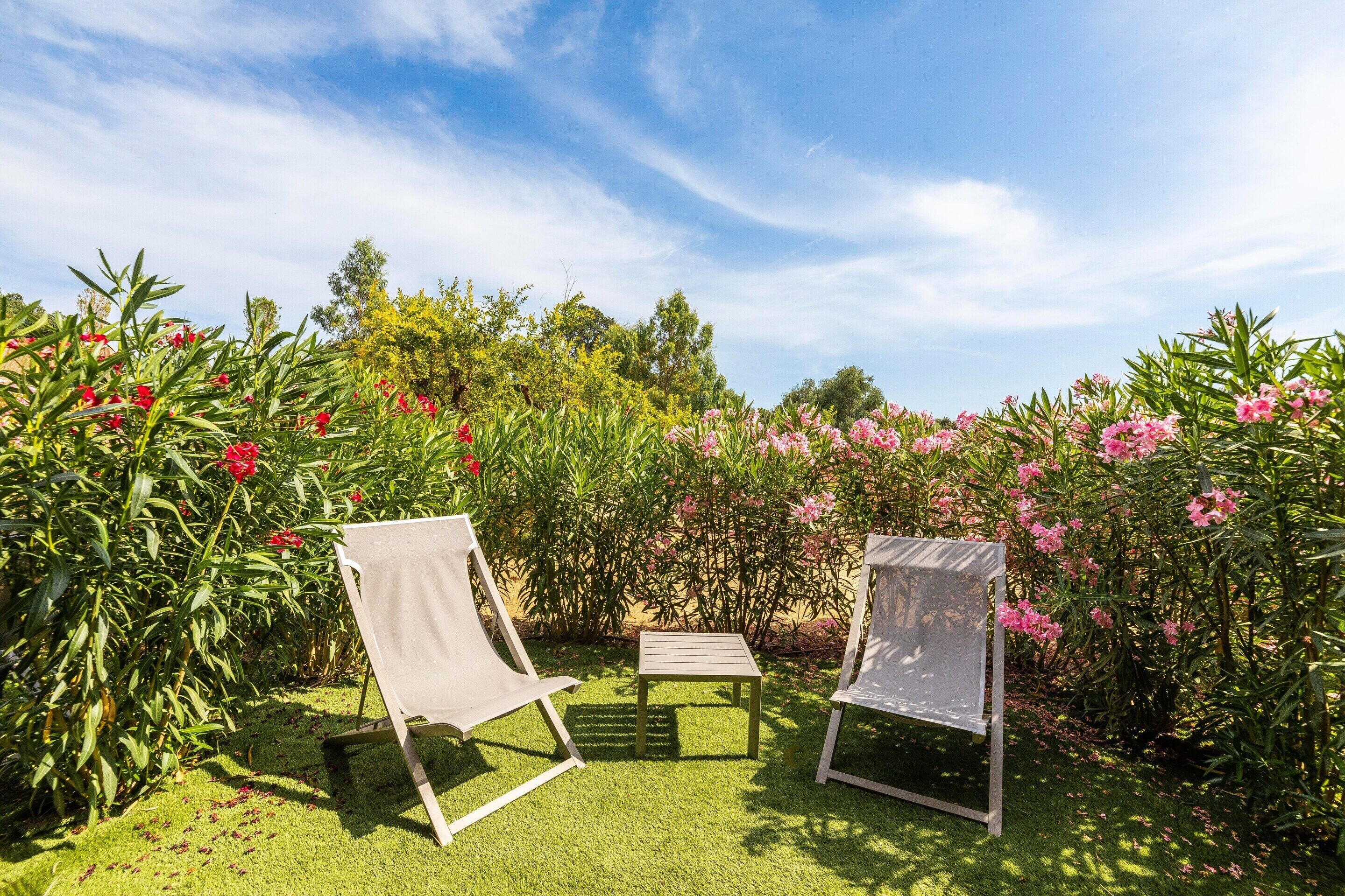 Deux fauteuils confortables, une petite table et une végétation luxuriante agrémentée de plantes à fleurs.