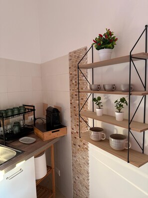 A kitchen with a coffee maker, a shelf with mugs, and a brick accent wall. - Apartment with terrace for exclusive use 30 m from Palermo Cathedral (Palermo)
