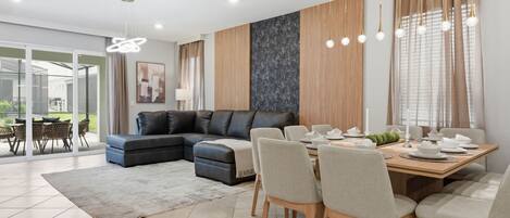 A modern living room with a sectional sofa, dining table, and chairs.