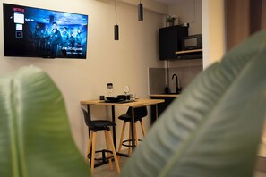 Eine moderne Küche mit Flachbildfernseher, der eine Sendung zeigt, einem Esstisch mit Stühlen und einer Mikrowelle darüber.