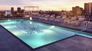 Ein Pool auf dem Dach mit Liegestühlen und Blick auf die Stadt.