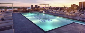 Ein Pool auf dem Dach mit Liegestühlen und Blick auf die Stadt.