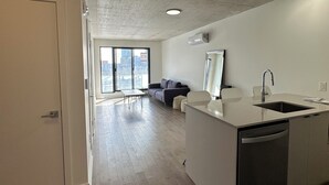 Eine moderne Küche mit einer zentralen Kochinsel, einem Essbereich mit Tisch und Stühlen sowie einem großen Fenster mit Blick auf die Stadt.