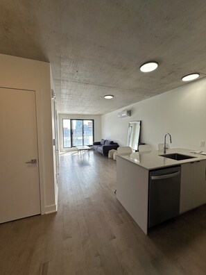 Eine moderne Küche mit einer zentralen Kochinsel, einem Essbereich mit Tisch und Stühlen sowie einem großen Fenster mit Blick auf die Stadt.