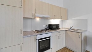 A kitchen with light wood cabinets, a built-in oven, a microwave, and a sink. - FarawayHomes Studio Krieglach 14 (Sommer)
