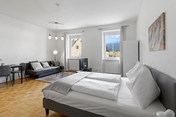 Un dormitorio moderno con una cama grande, un sofá, un escritorio y una televisión.