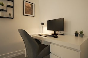 Un bureau moderne, Ă©quipĂ© dâun ordinateur, dâun clavier et dâune souris, ainsi que dâune chaise, dâune lampe de bureau et de deux plantes en pot.
