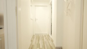 Ein Flur mit Holzboden, weißen Wänden und einer verschlossenen Tür am Ende.