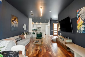 A modern living room with a sofa, coffee table, and a TV. - 3BR East Austin Unit A - Sleeps 10, Pet Friendly (Austin)