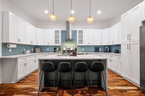 A modern kitchen with white cabinets, a central island with bar stools, and pendant lighting. - 3BR East Austin Unit B - Sleeps 10, Pet Friendly (Austin)