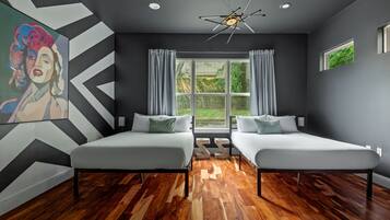 Une chambre moderne avec deux lits, une grande fenêtre et un luminaire au plafond au design original.