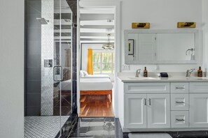 A modern bathroom with a shower, a large mirror, and a vanity with a sink and cabinets. - 6BR East Austin Complex - Sleeps 20 - Pet Friendly (Austin)
