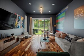 Un salon moderne doté d’un téléviseur à écran plat, d’un canapé, d’une table basse et d’un coin repas avec des chaises.