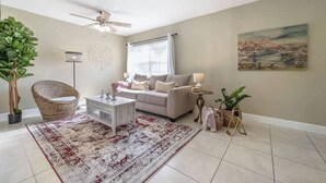 A living room with a sofa, coffee table, floor lamp, and potted plants. - The Parkside Palm - Tampa retreat for 6 (Tampa)