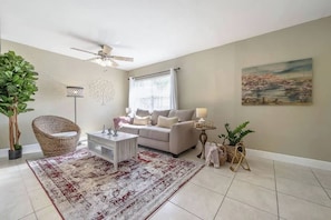 A living room with a sofa, coffee table, floor lamp, and potted plants. - The Parkside Palm - Tampa retreat for 6 (Tampa)