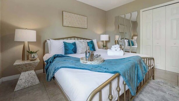 A bedroom with a bed, bedside lamps, a mirror, and a wardrobe. - The Parkside Palm - Tampa retreat for 6 (Tampa)