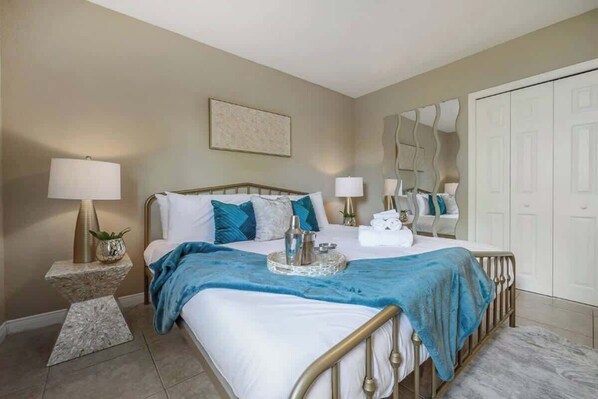 A bedroom with a bed, bedside lamps, a mirror, and a wardrobe. - The Parkside Palm - Tampa retreat for 6 (Tampa)