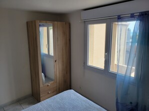 Ein Schlafzimmer mit Holzschrank, einem Bett, einem Fenster mit Blick und einem Vorhang.